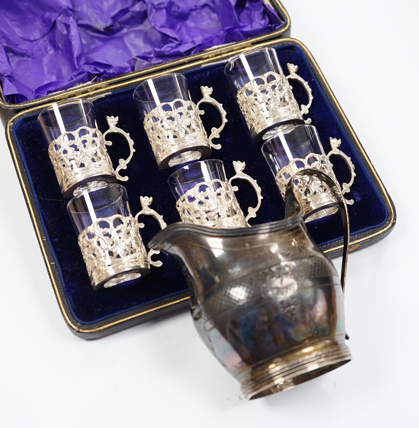 A George III engraved silver helmet shaped cream jug, Francis Purton?, London, circa 1790, height 10.6cm (a.f.), together with a cased set of six George V silver coffee can holders, with glass inserts, Marples & Co, Birm